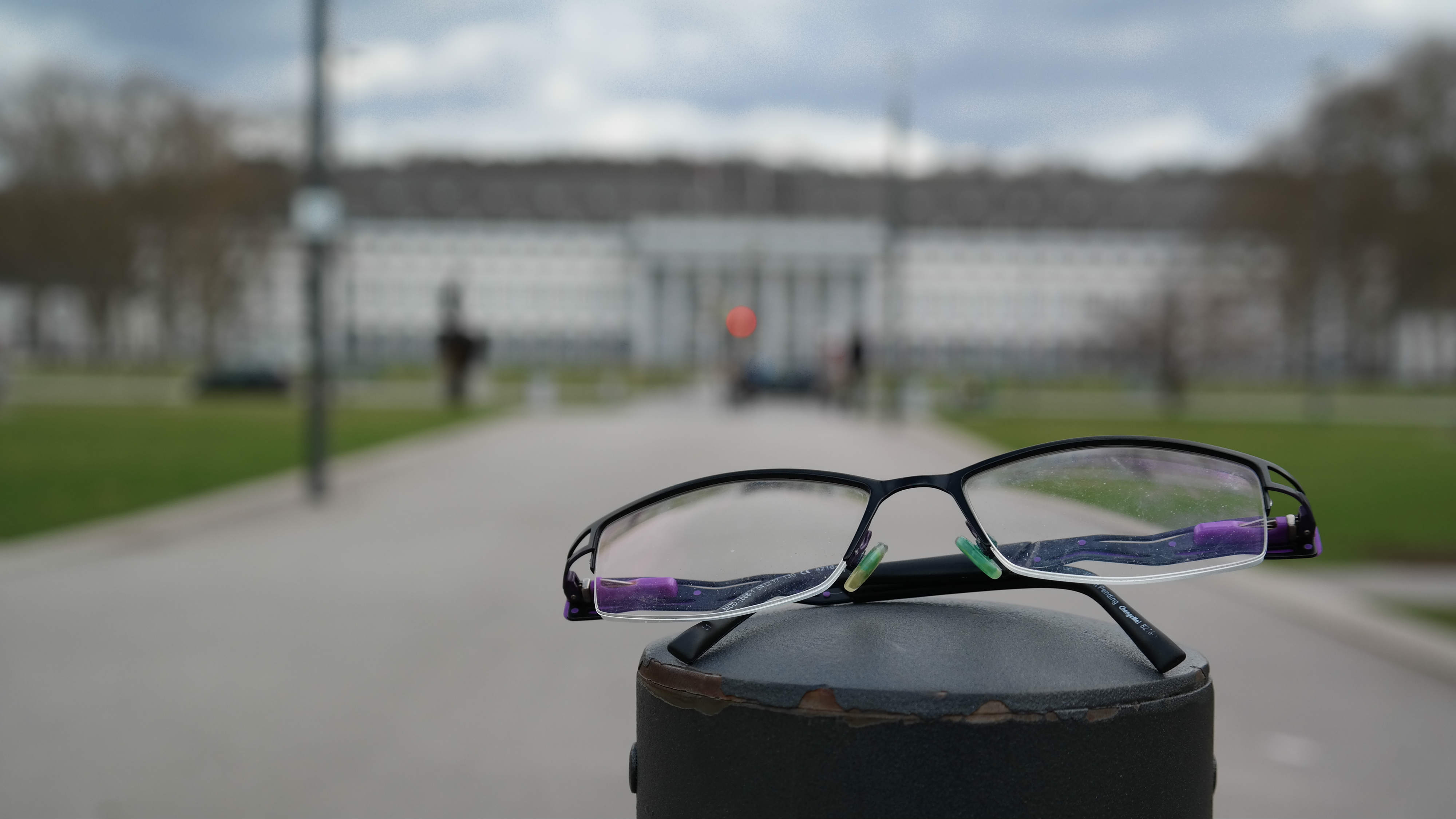 Eine Brille von Fielmann liegt in einem Park vor dem Schloss.