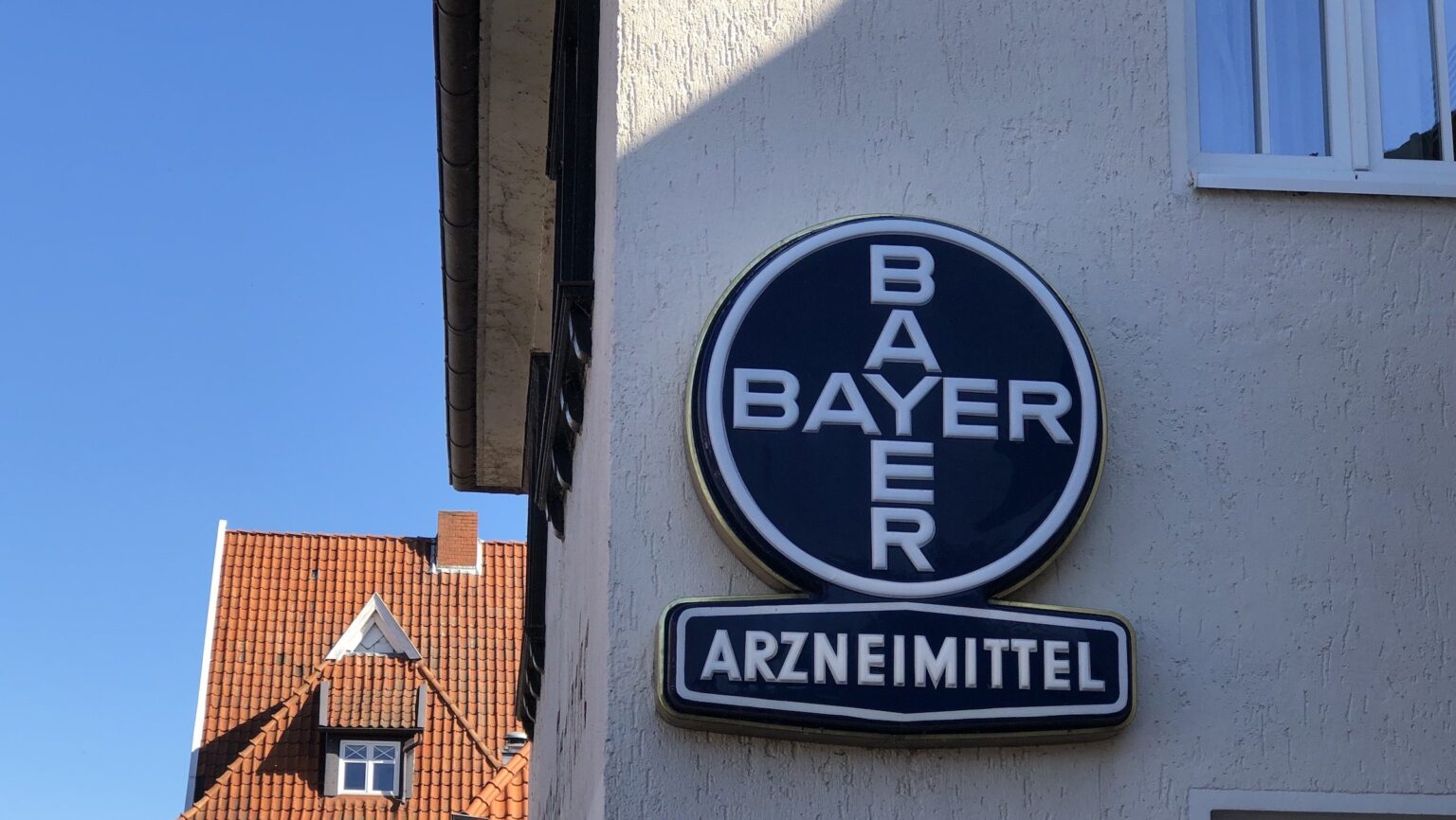 Ein altes Bayer-Logo an einer Apotheke, das für Arzneimittel wirbt