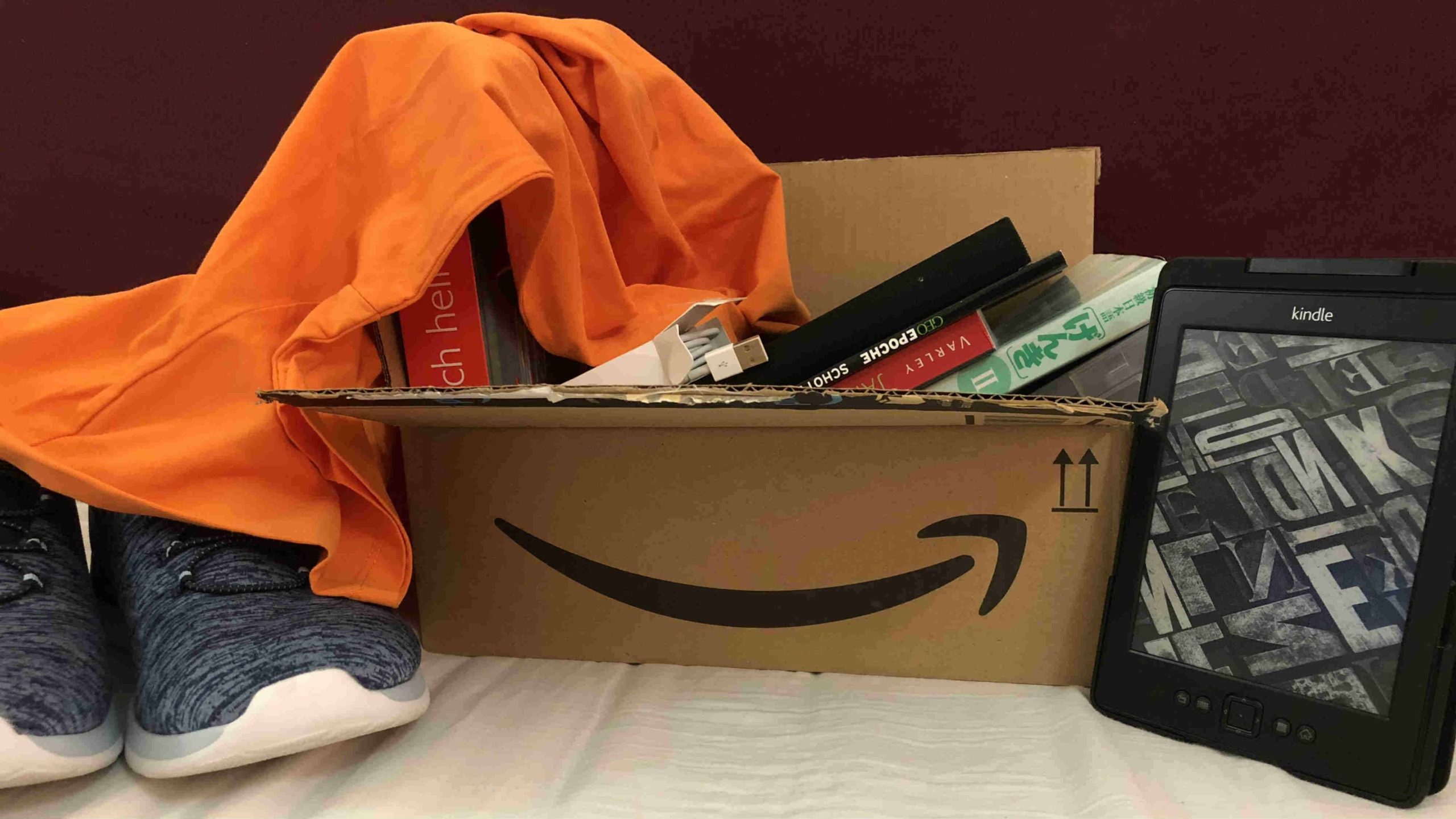 Verschiedene Käufe von Amazon mit einem Paket mit Amazonlogo. Schuhe, Bücher und ein Kindle.