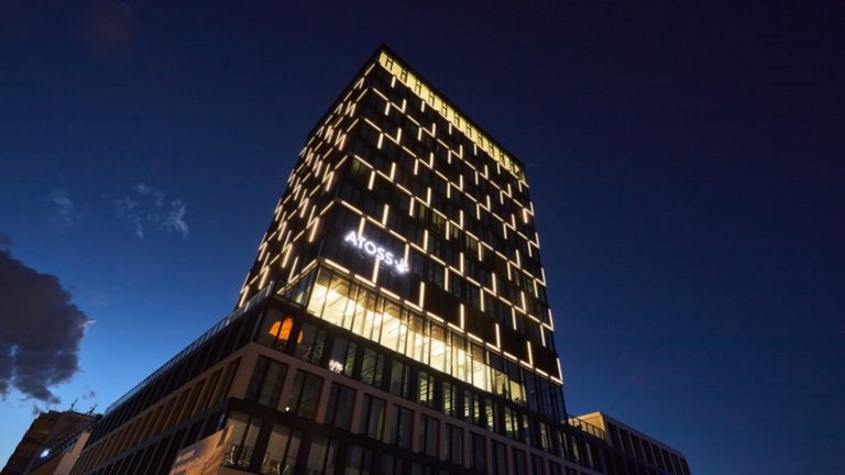 Beleuchtetes Hochhaus der Atoss AG in der Nacht mit Wolken im Hintergrund