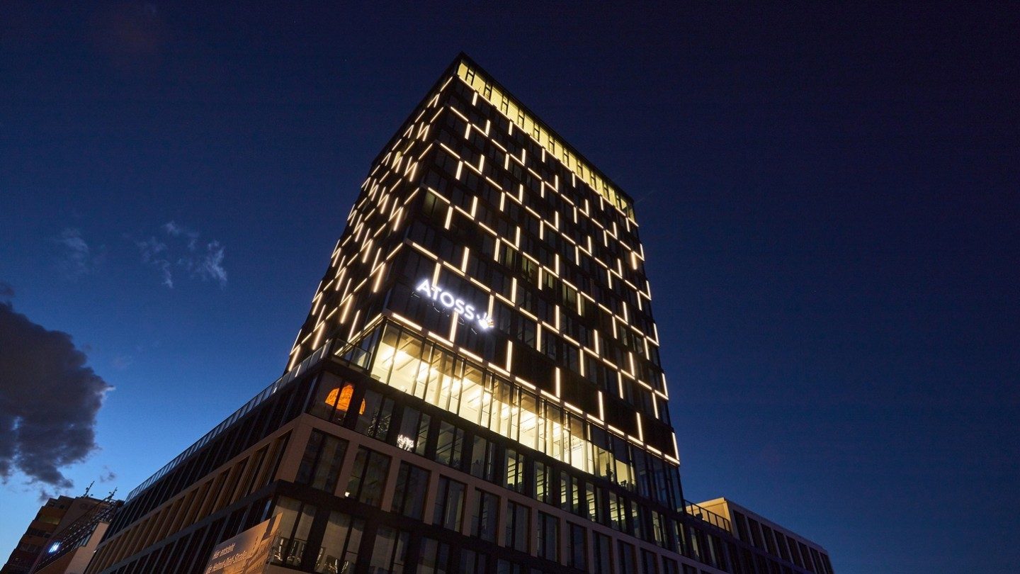 Beleuchtetes Hochhaus der Atoss AG in der Nacht mit Wolken im Hintergrund