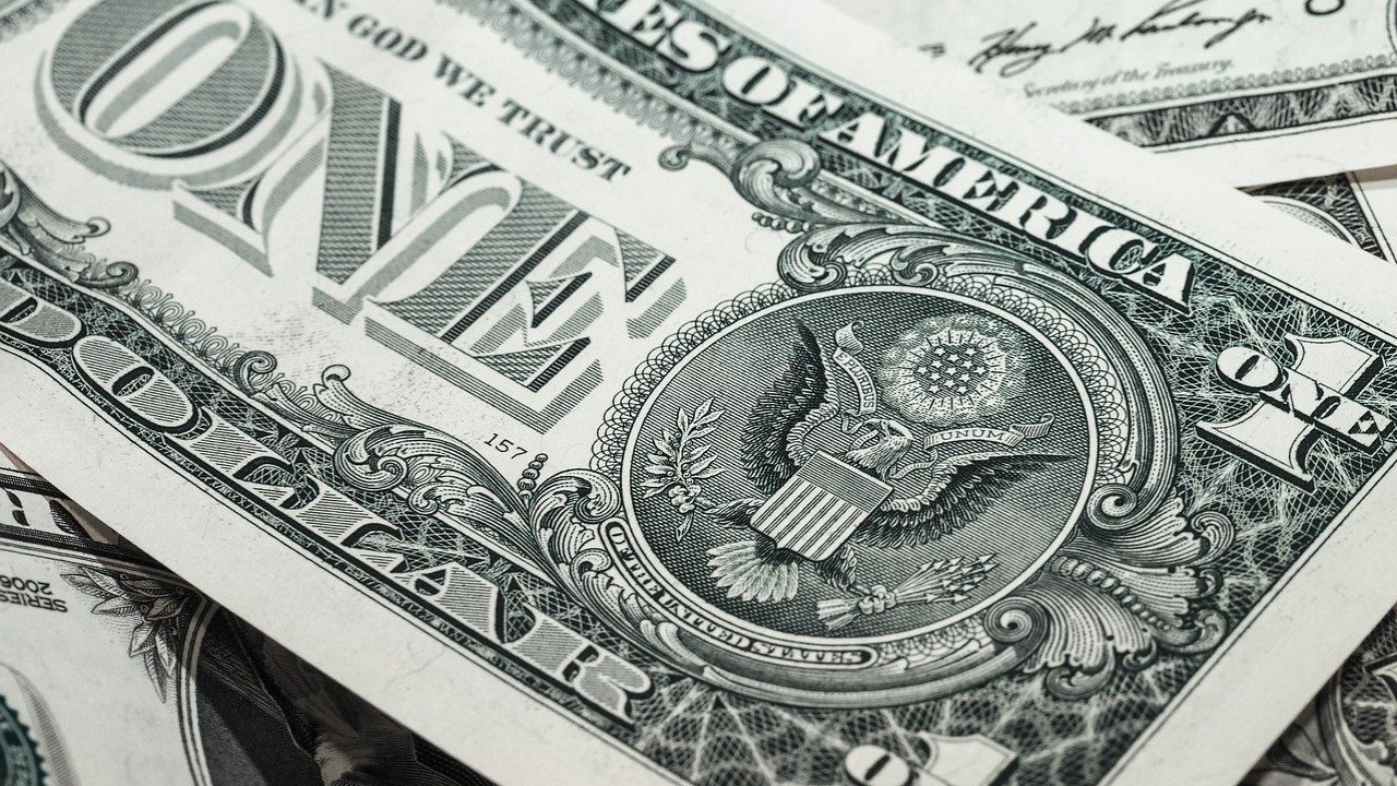 Eine Dollarbanknote mit einem Adler liegt auf einen Stabel von Dollarscheinen.