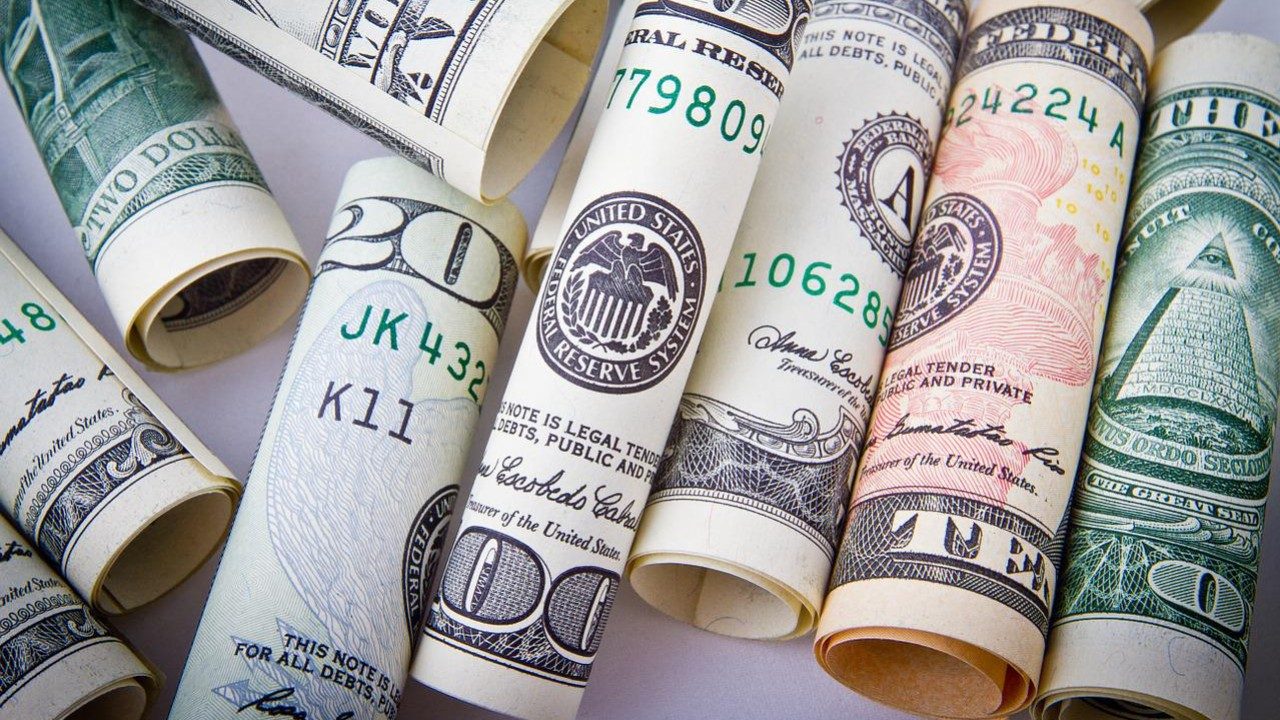 eingerollte US-Dollar-Geldscheine liegen auf einem Tisch