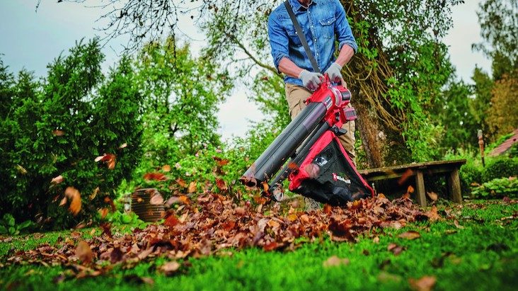 Ein Mann säubert mit einem Einhell-Laubbläser seinen Garten