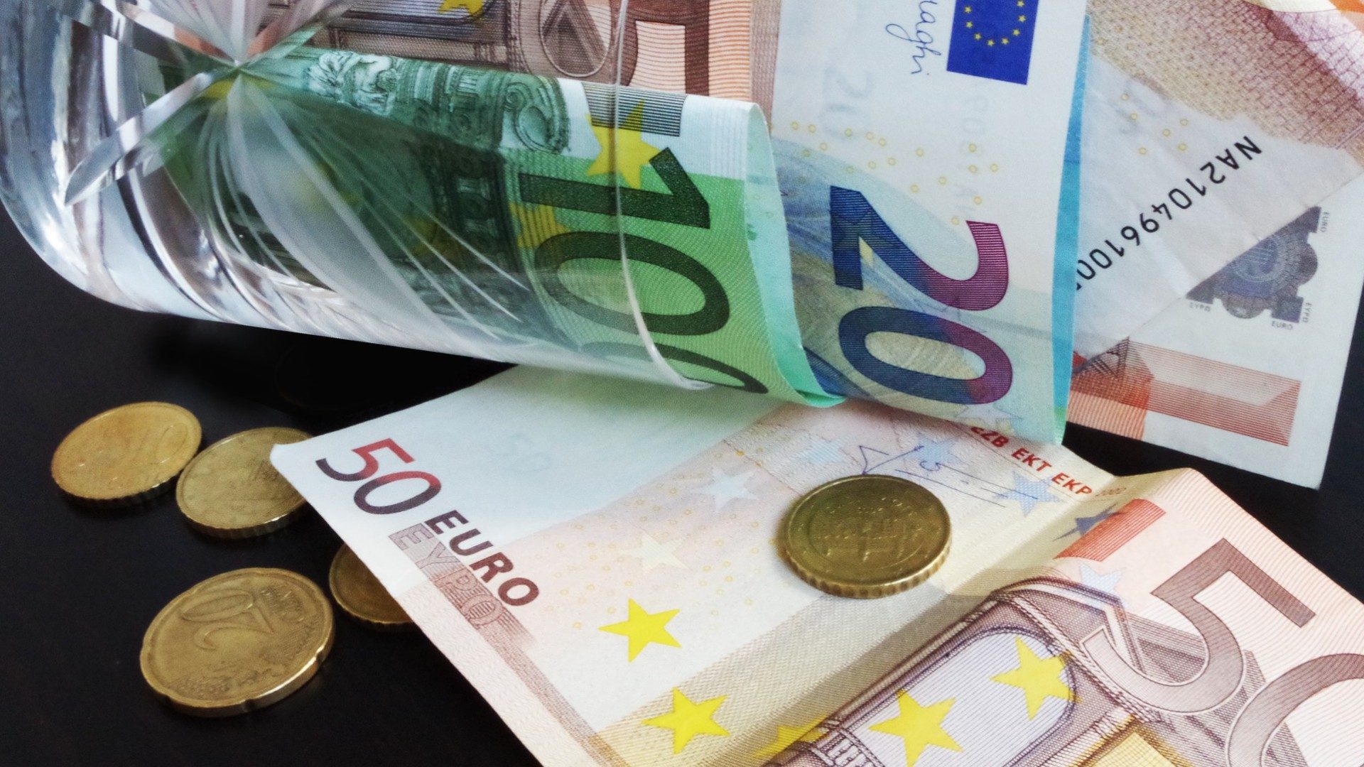 Euro-Münzen und Geldscheine liegen auf einem Tisch verteilt