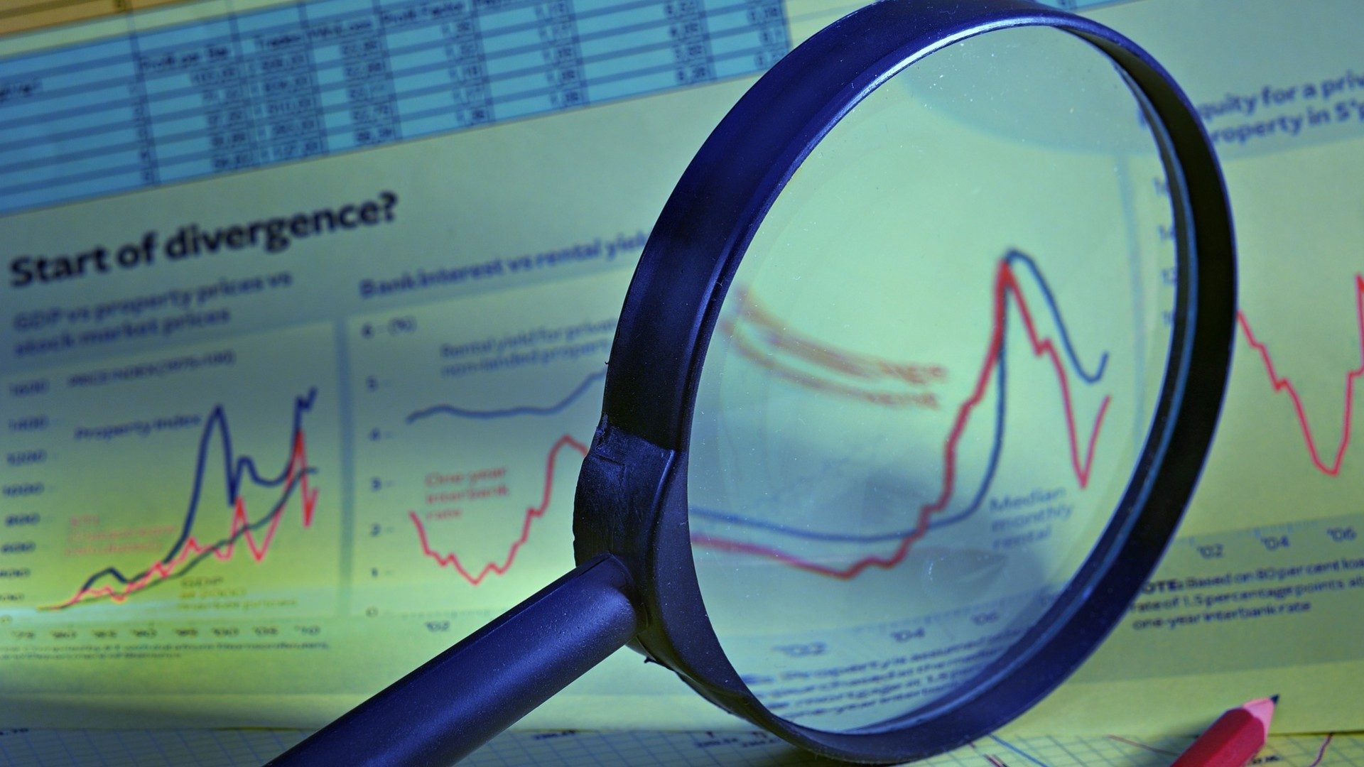 Eine Lupe vergrößert Charts auf einem Datenanalyse-Blatt