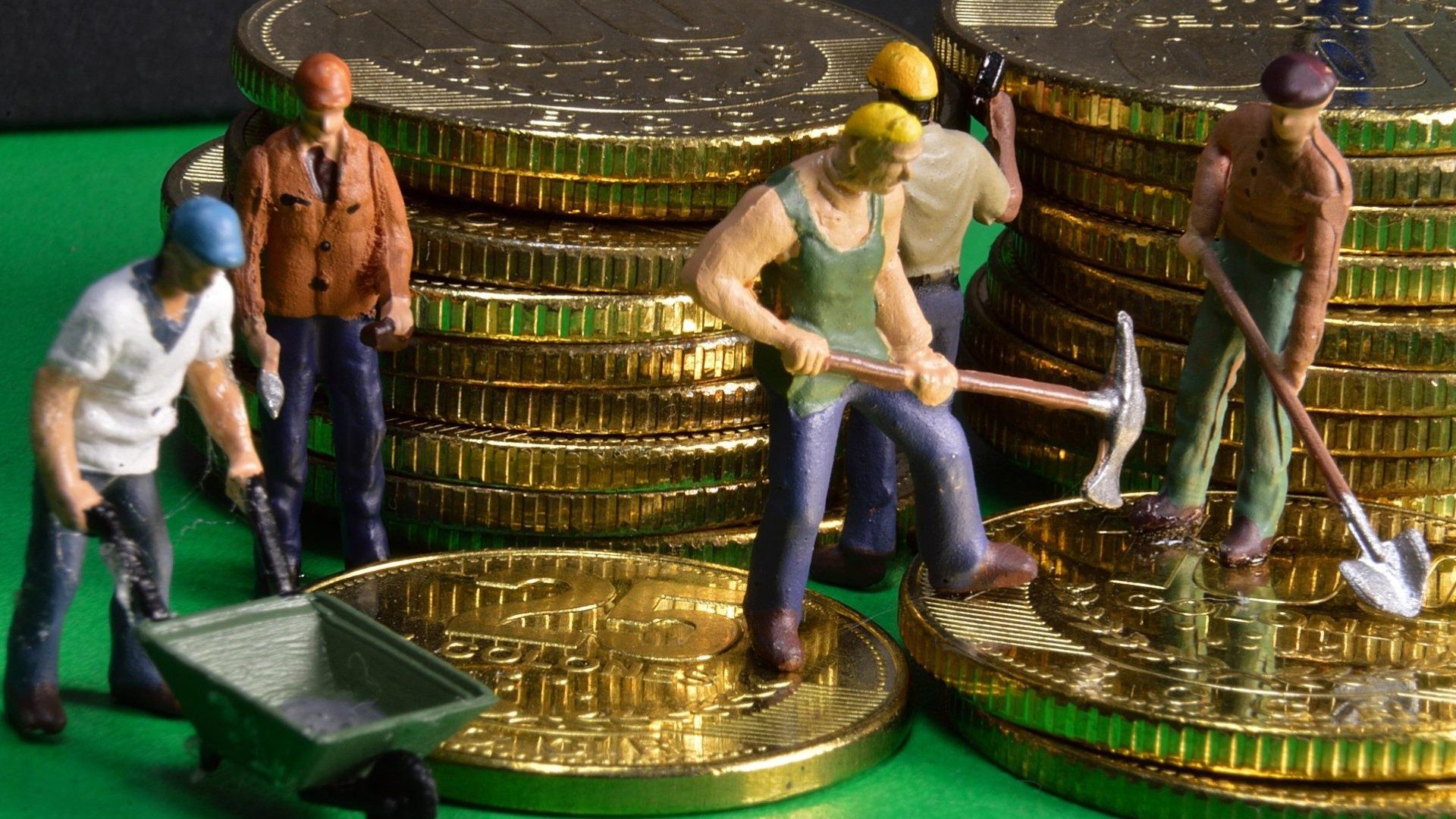 Figuren von Arbeitern stehen auf Stapeln von Geldmünzen