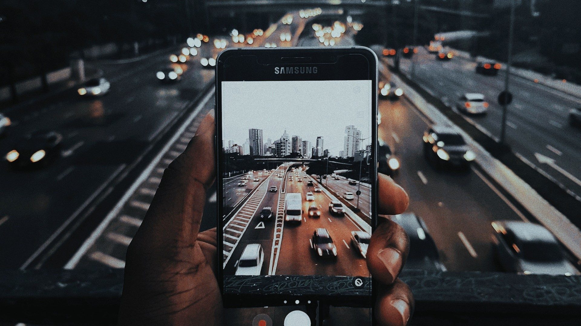 Eine Person macht mit einem Samsung-Smartphone ein Foto einer Straße mit viel Verkehr
