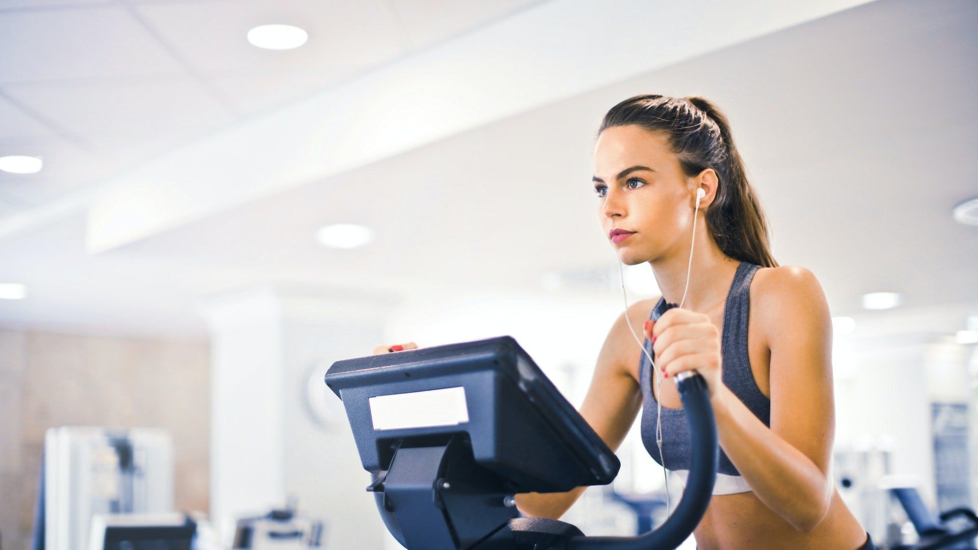 Eine Frau mit Kopfhörern beim Training auf einem Sportgerät im Fitnessstudio