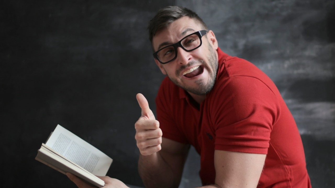 Ein Mann mit Brille liest ein Buch, aber schaut drein wie ein Depp und versteht nichts