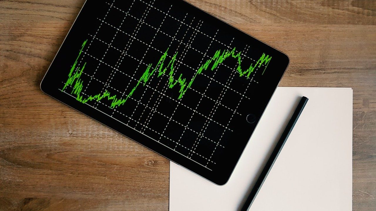 Ein grüner Aktien-Chart auf einem Tablet nebst Stift und Papier