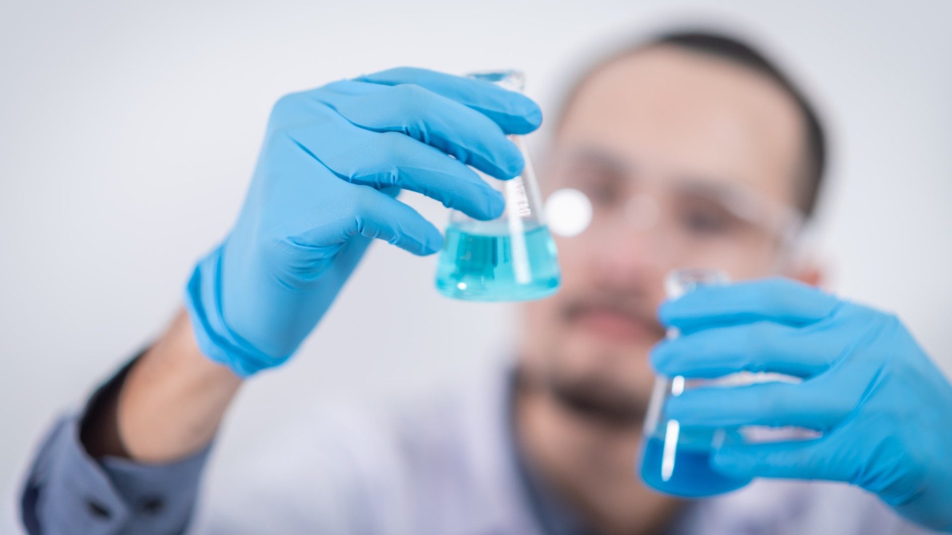 Ein Mann im Labor vergleicht zwei blaue Reagenzen