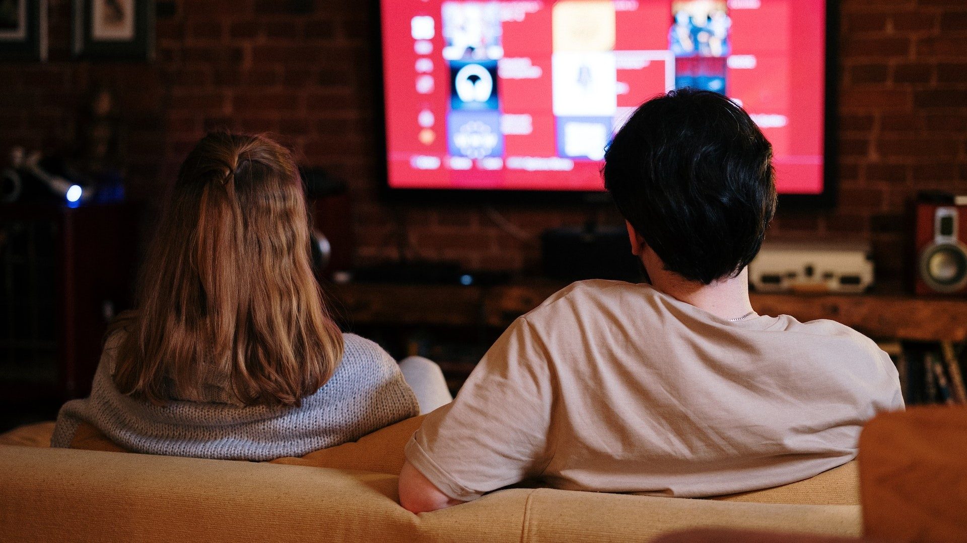 Ein Paar sitzt auf der Couch vor dem TV zum Fernsehen oder Streamen