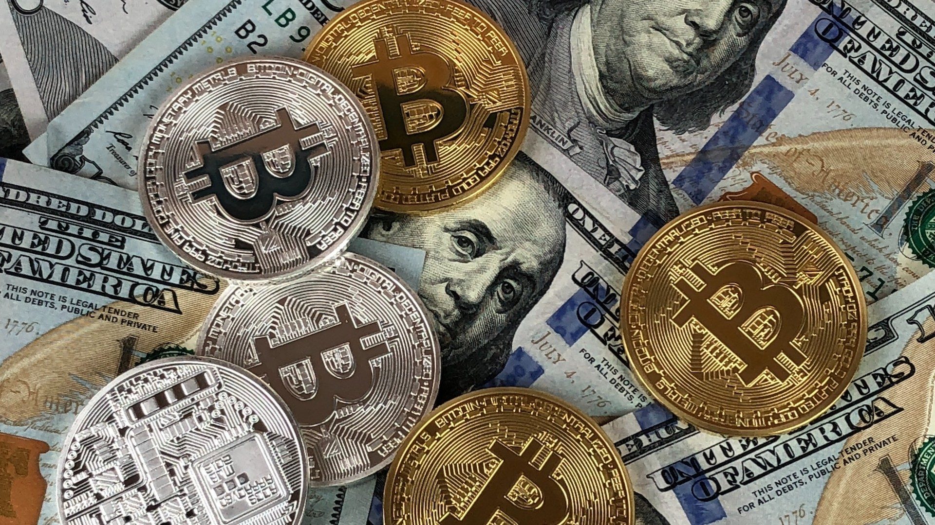 Silberne und goldene Bitcoin-Münzen liegen auf Banknoten von US-Dollar-Fiatgeld