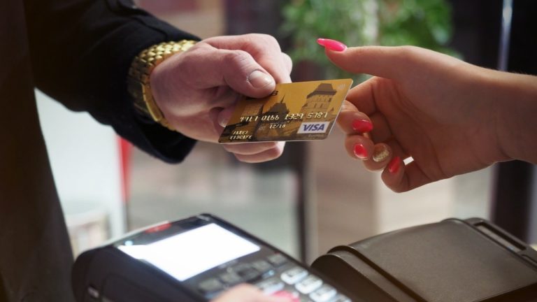 Eine Person bezahlt im Einzelhandel mit einer goldenen Visa Kreditkarte