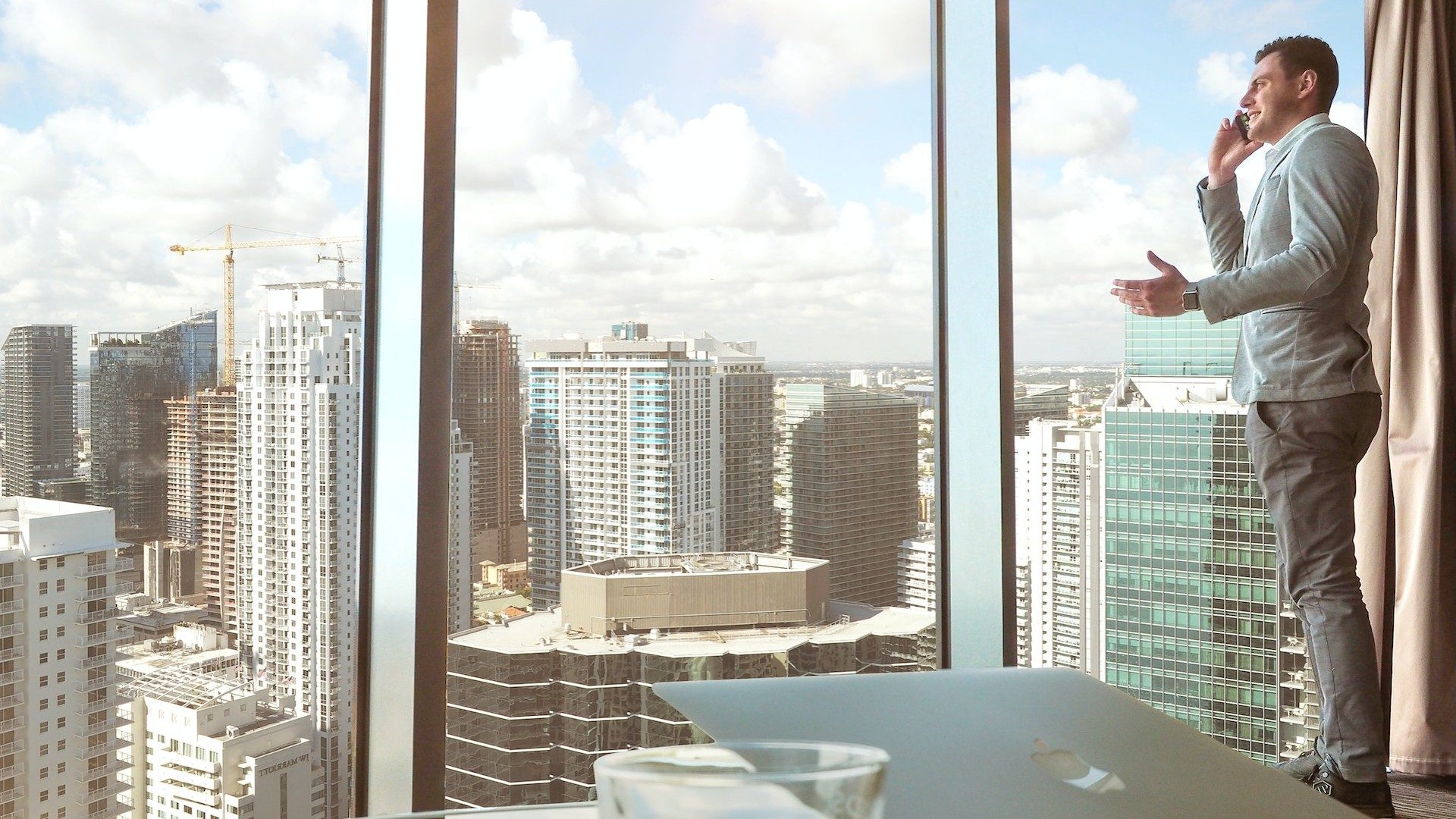 Ein Geschäftsmann spricht am Handy, hinter ihm die Skyline einer Metropole mit vielen Hochhäusern