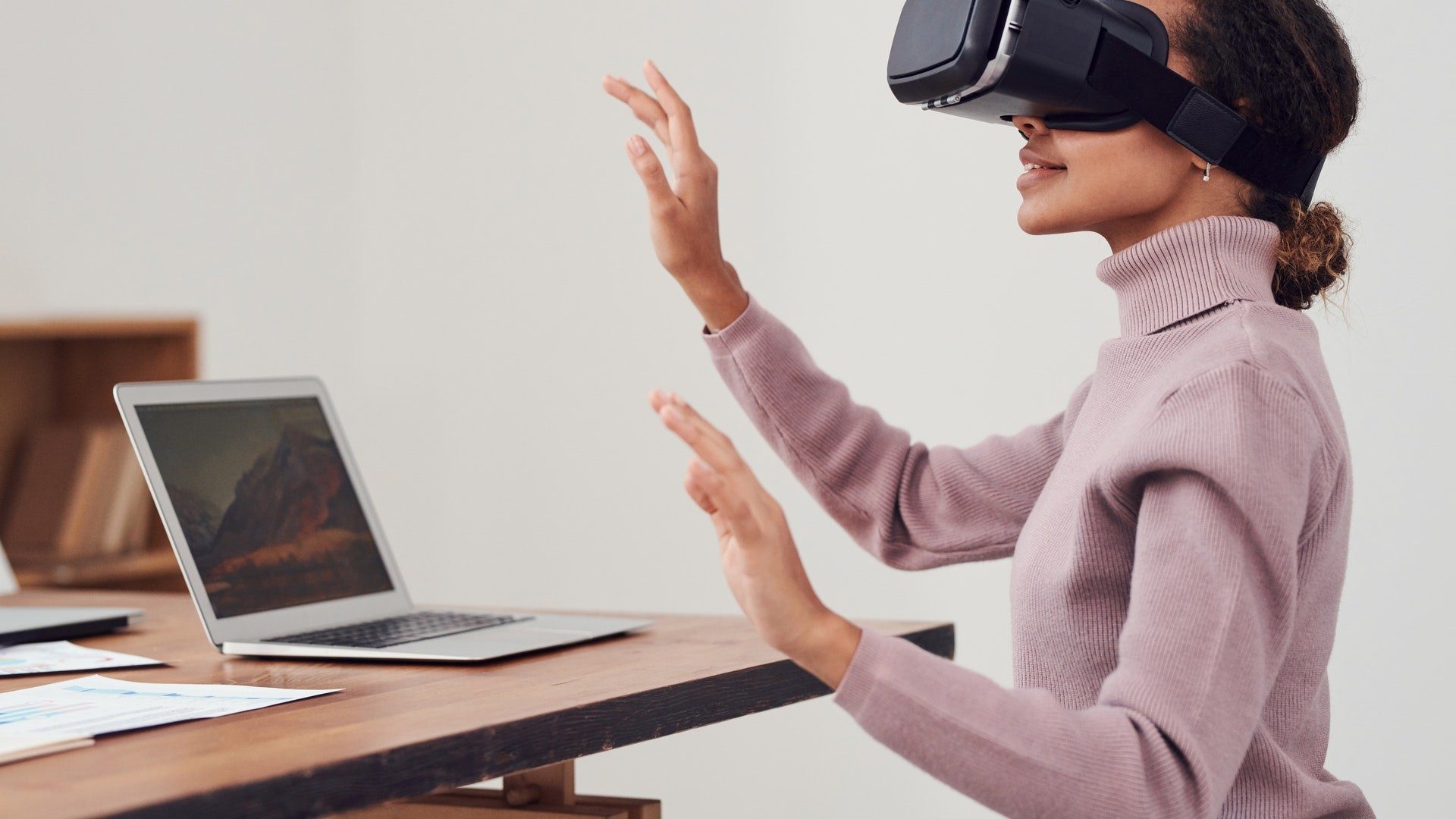 Eine Frau sitzt mit Virtual Reality (VR)-Brille vor ihrem Laptop – der Einstieg ins Metaverse