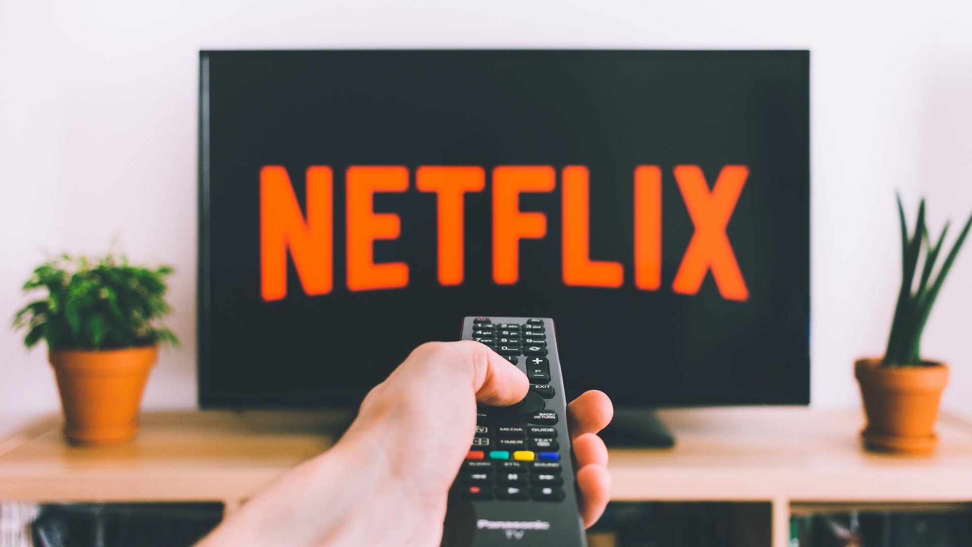 Eine Person mit Fernbedienung startet den Streamingdienst Netflix auf dem Fernseher