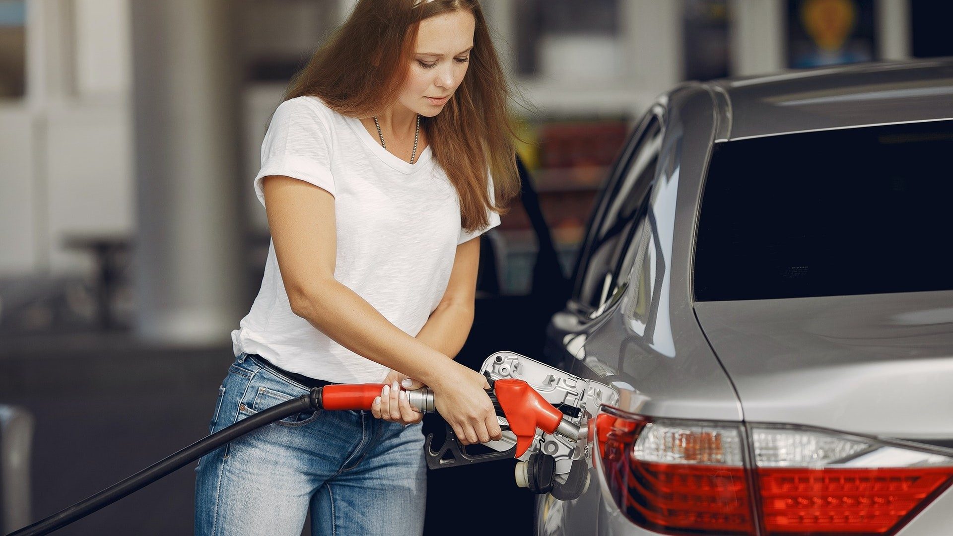 Eine Frau füllt an der Tankstelle Benzin in ihr Auto