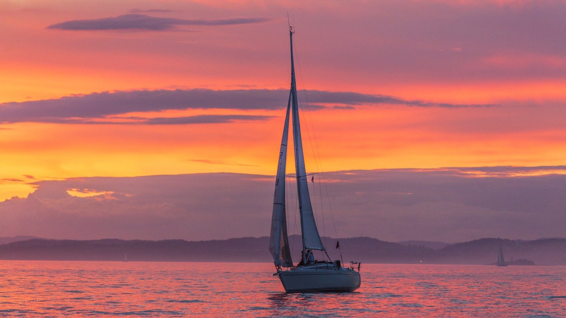 Ein Segelboot lässt sich vom Wind in den Sonnenuntergang treiben