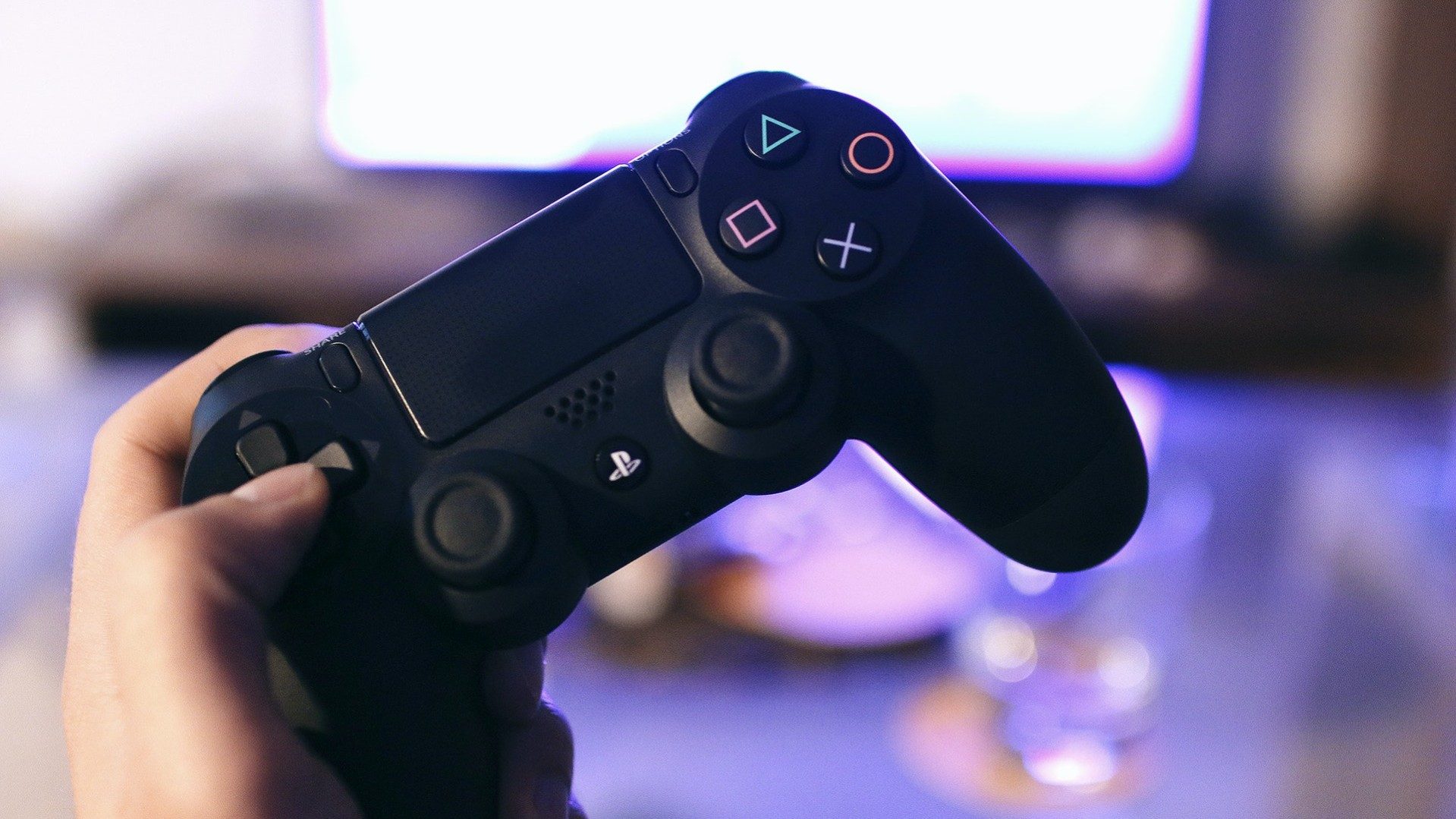 Eine Person hält einen Sony Playstation-Controller um Videospiele zu spielen