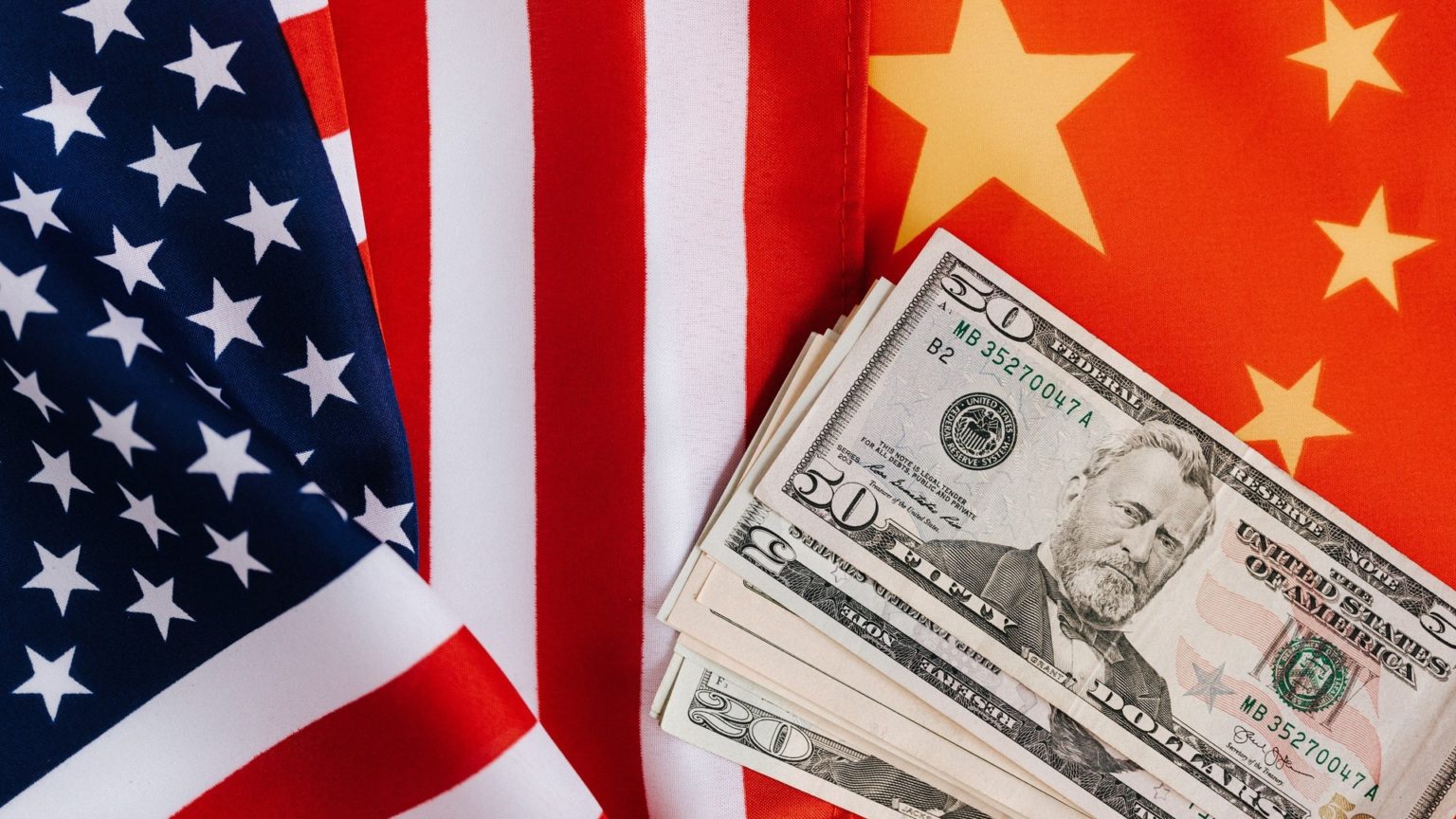Die Flaggen der USA und von China mit amerikanischen Dollar-Geldscheinen