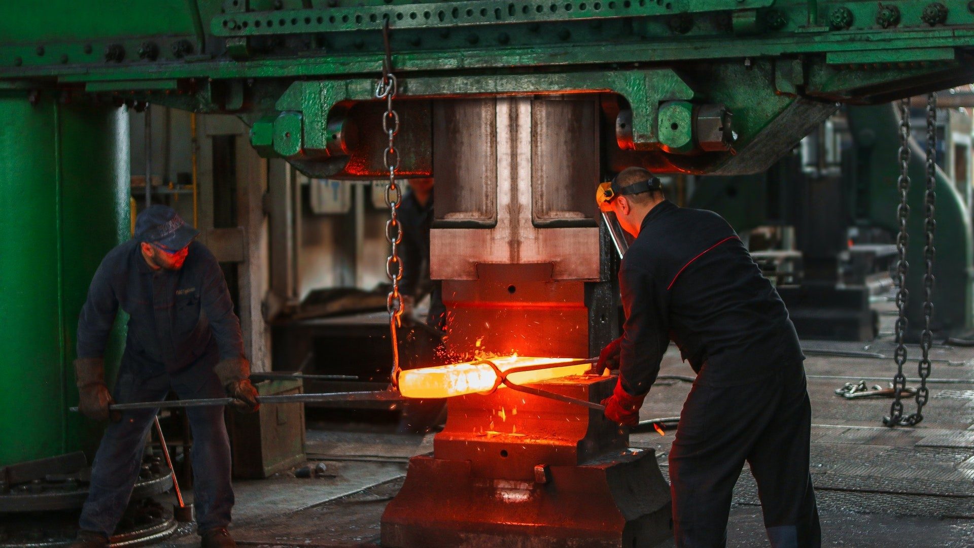Zwei Männer schmieden glühend heißen Stahl oder anderes Metall