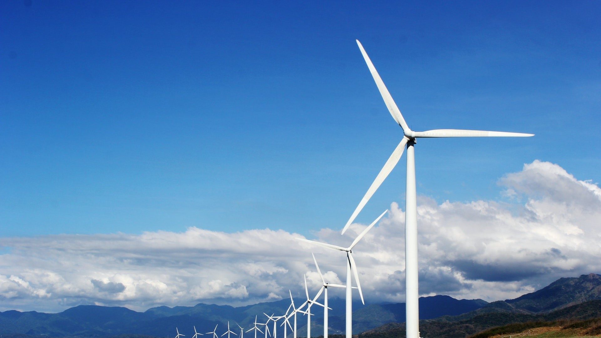 Eine Reihe von Windrädern produziert an einem sonnigen Tag grünen Strom