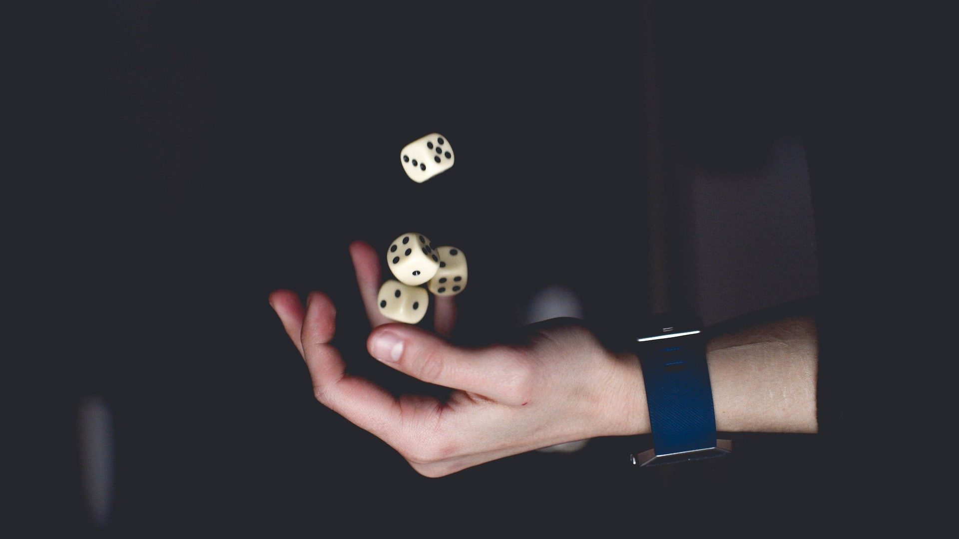 Eine Person jongliert mit vier Würfeln, die für Zufall und Glücksspiel stehen