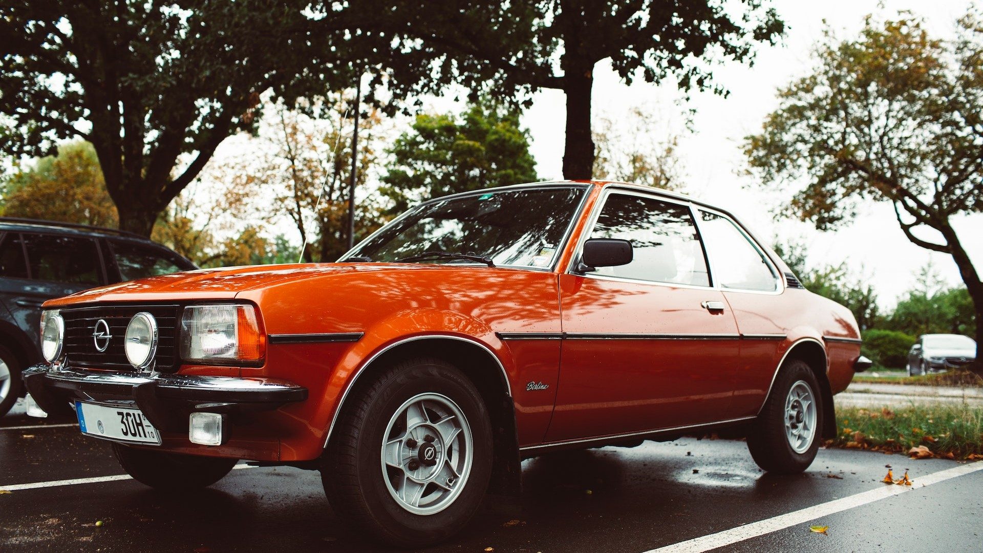 Ein oranger Oldtimer der Stellantis-Marke Opel auf einem Parkplatz
