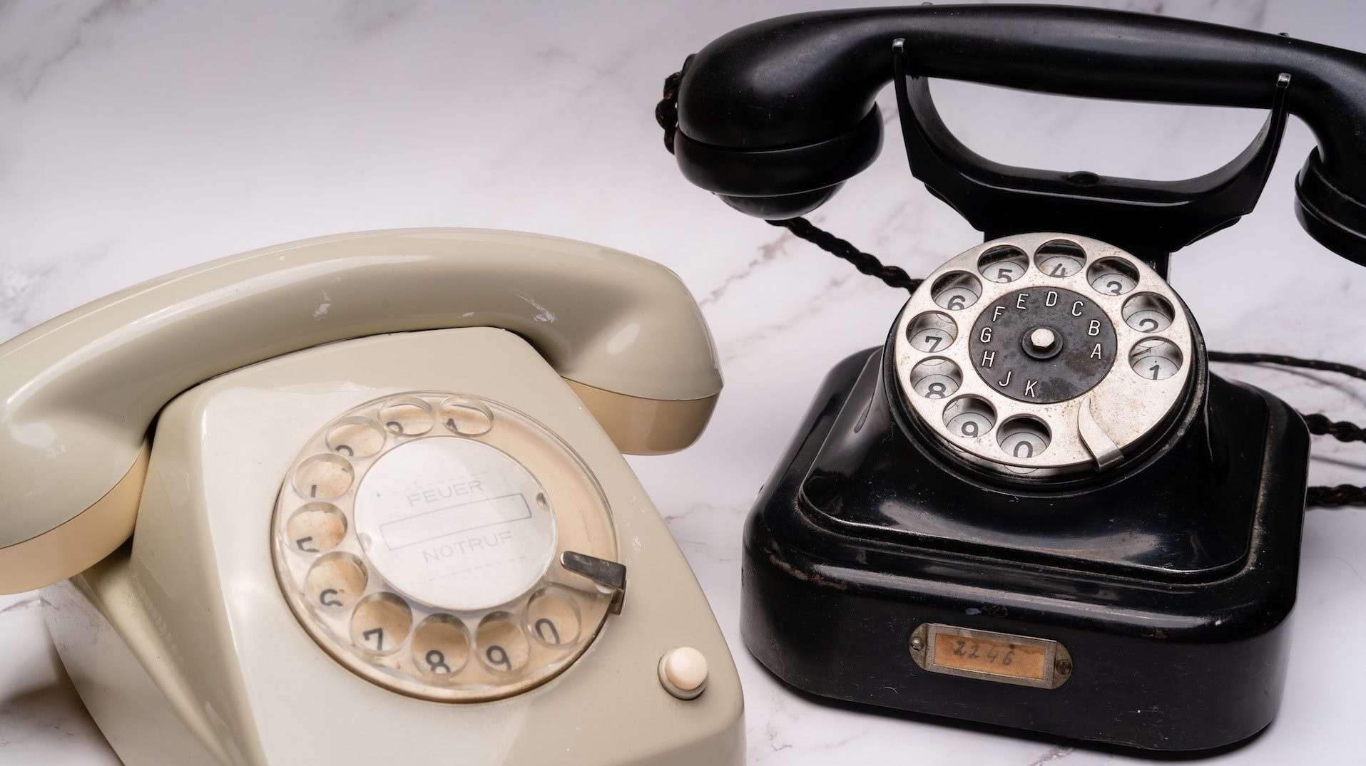 Alte Technologie: zwei Wählscheibentelefone auf einem Marmortisch
