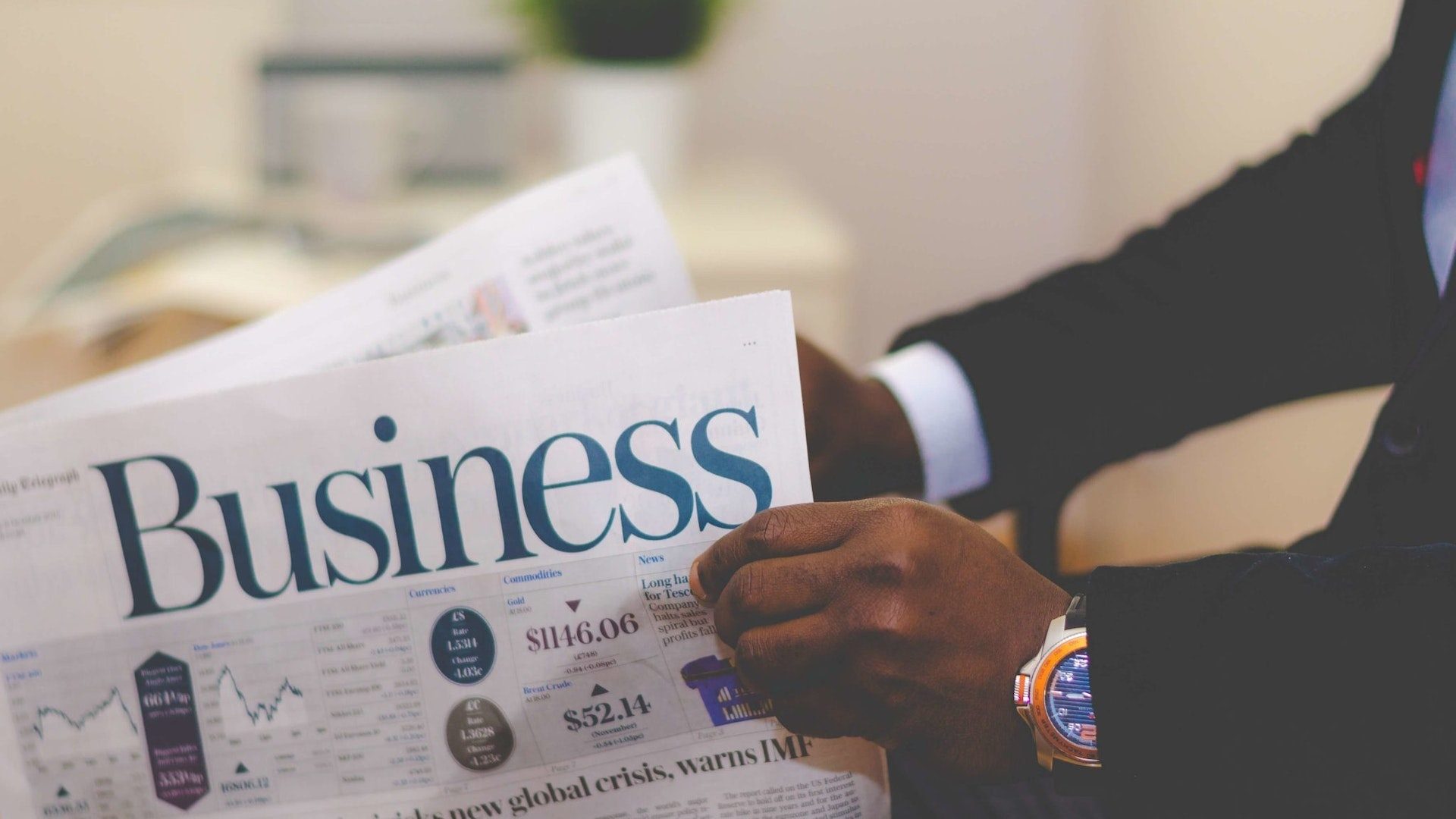 Ein Geschäftsmann im Anzug liest in einer Wirtschaftszeitung mit dem Aufdruck "Business" die Nachrichten