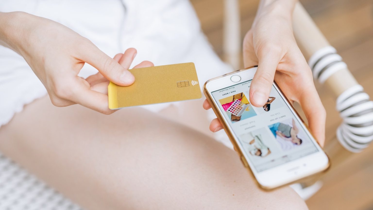 Eine Frau mit Smartphone und Kreditkarte kauft bei Onlinehändlern ein
