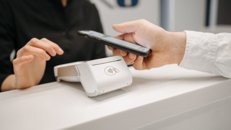 Eine Person bezahlt im Einzelhandel kontaktlos mit dem Smartphone