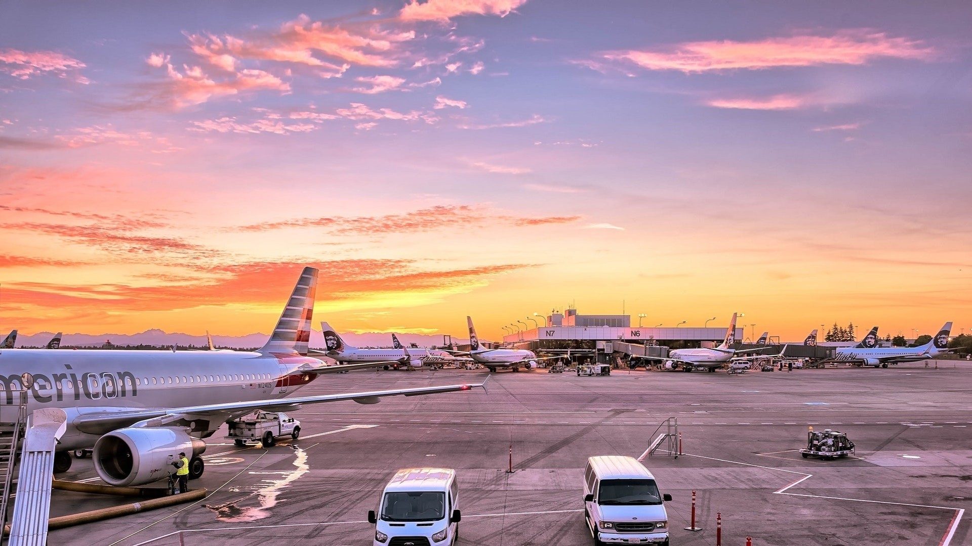 Auf einem Flughafen im Sonnenuntergang stehen Flieger mehrerer Airlines