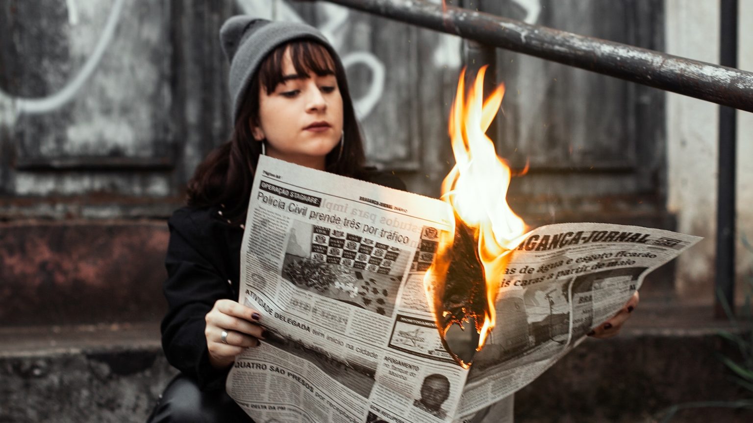 Heiße News: Eine Frau hält eine brennende Zeitung mit aktuellen Nachrichten