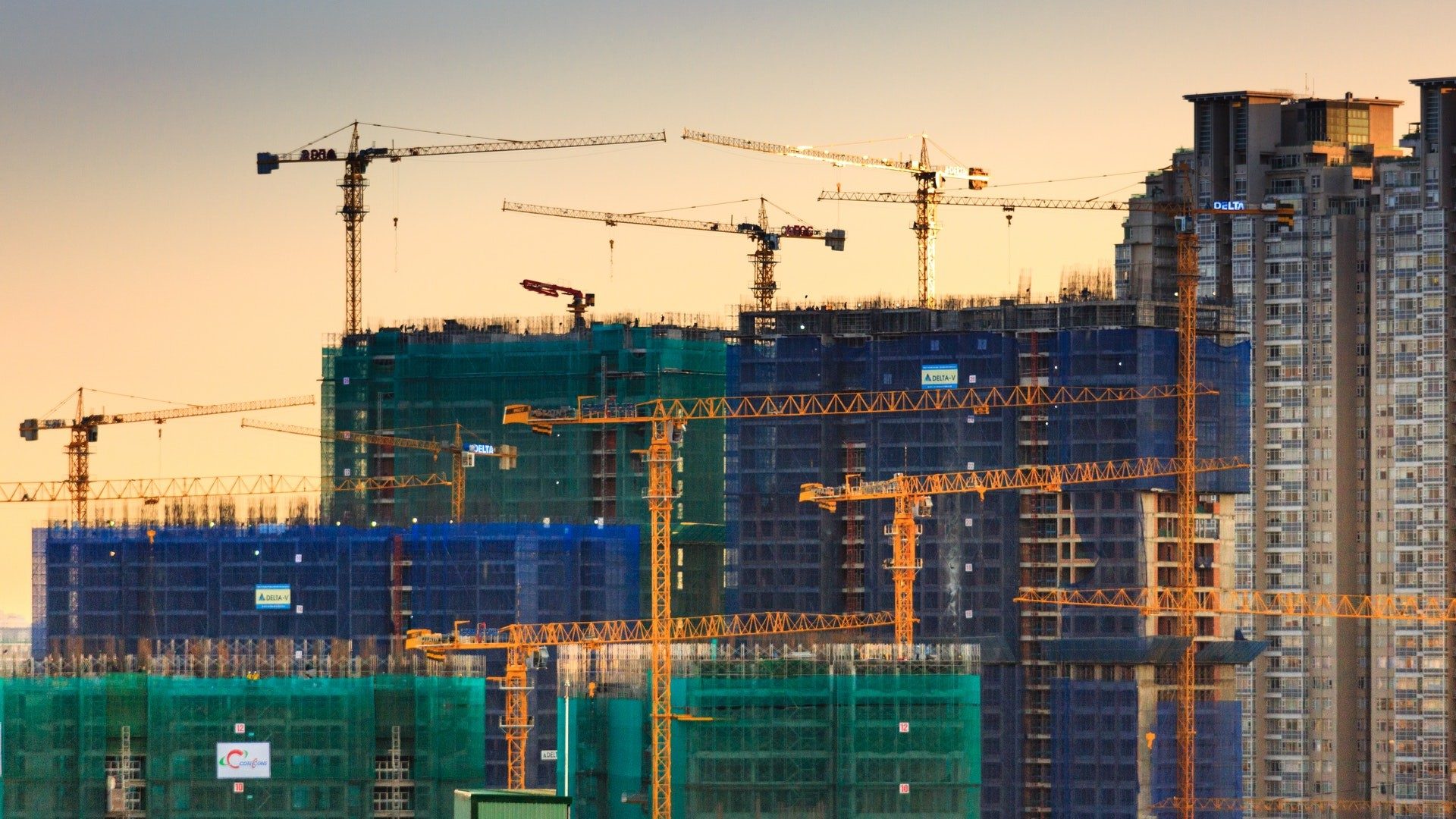 Blick auf einen Baustelle mit vielen Krans die gerade Hochhäuser bauen.