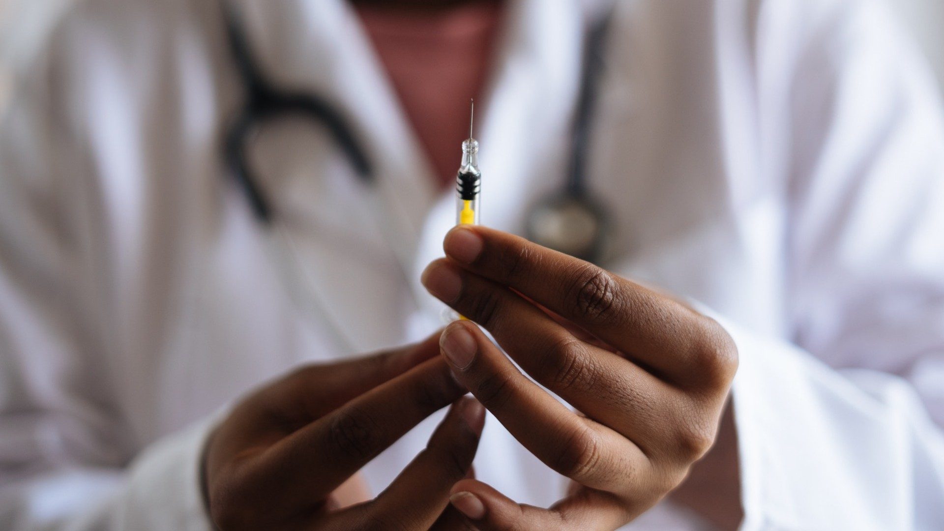 Ein Arzt hält eine Spritze mit einem Medikament oder einem Impfstoff.
