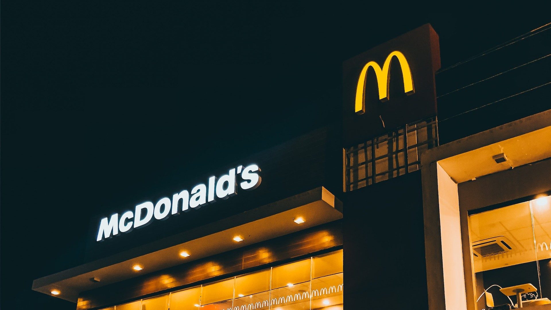 Schriftzug und Logo der Fastfood-Kette McDonald's an einer Filiale bei Nacht