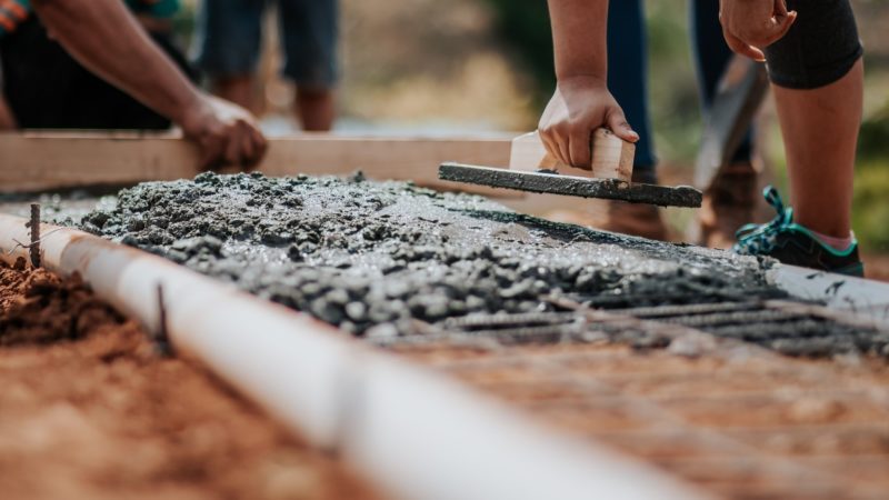 Personen ebnen auf der Baustelle Segment in eine Gitterstahlgerüst.
