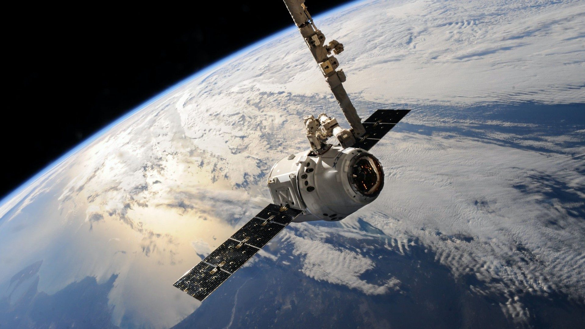 Ein Satellit der gerade um die Erde kreist mit der Erde im Hintergrund.