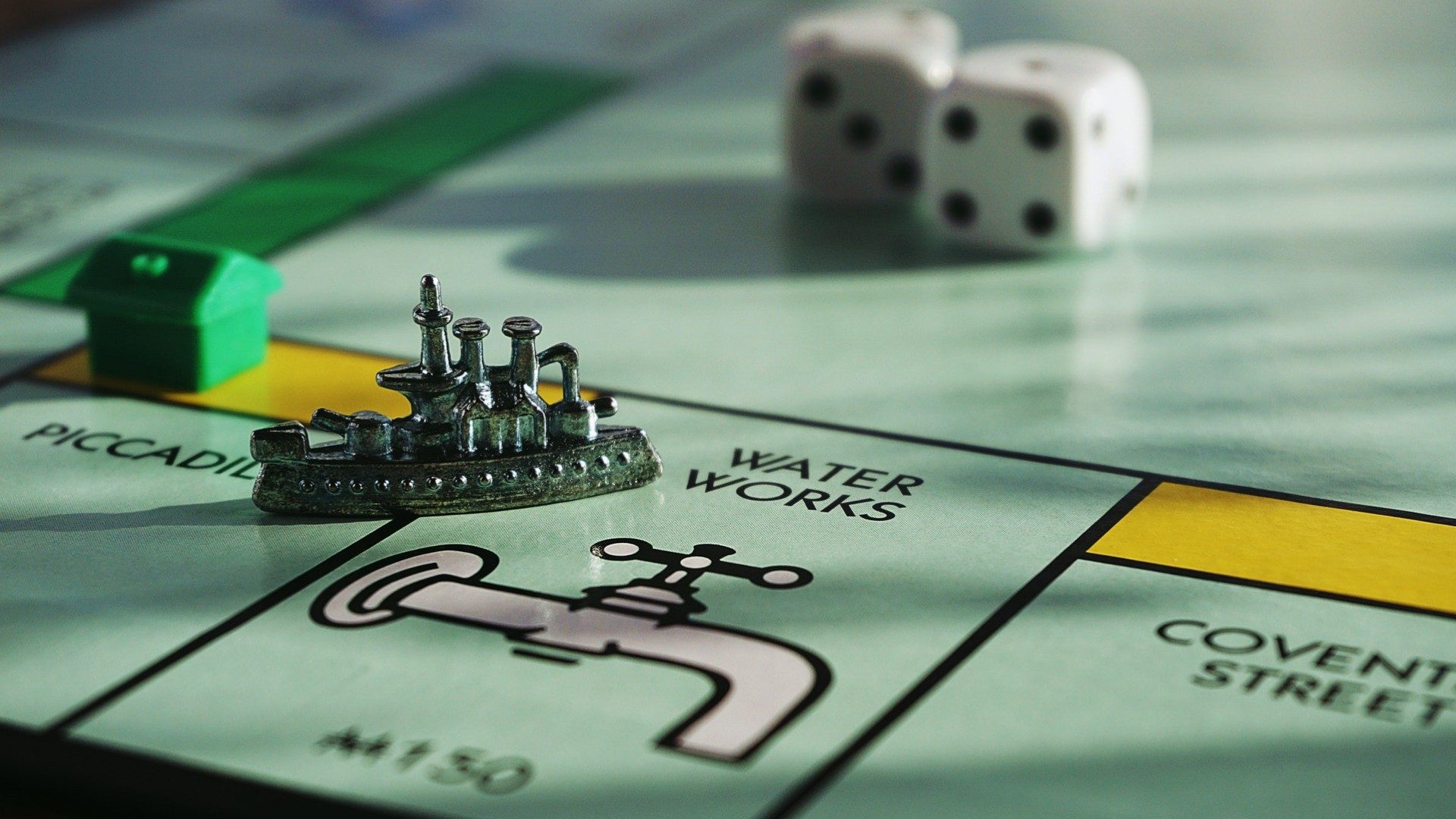 Ein Monopoly-Spiel mit einem Schiff als Spielfigur und Häusern und Würfeln im Hintergrund.