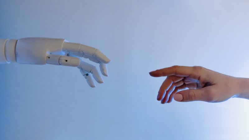 Eine Roboterhand und eine Menschenhand versuchen sich zu berühren.