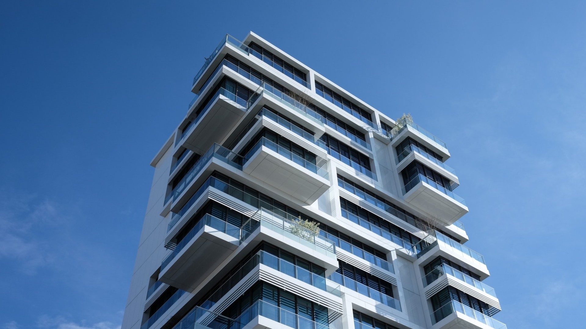 Blick von unten auf ein Hochhaus mit Wohnung mit blauen Himmel im Hintergrund.