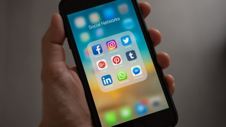 Eine Person hält ein iPhone mit Logos sozialer Medien