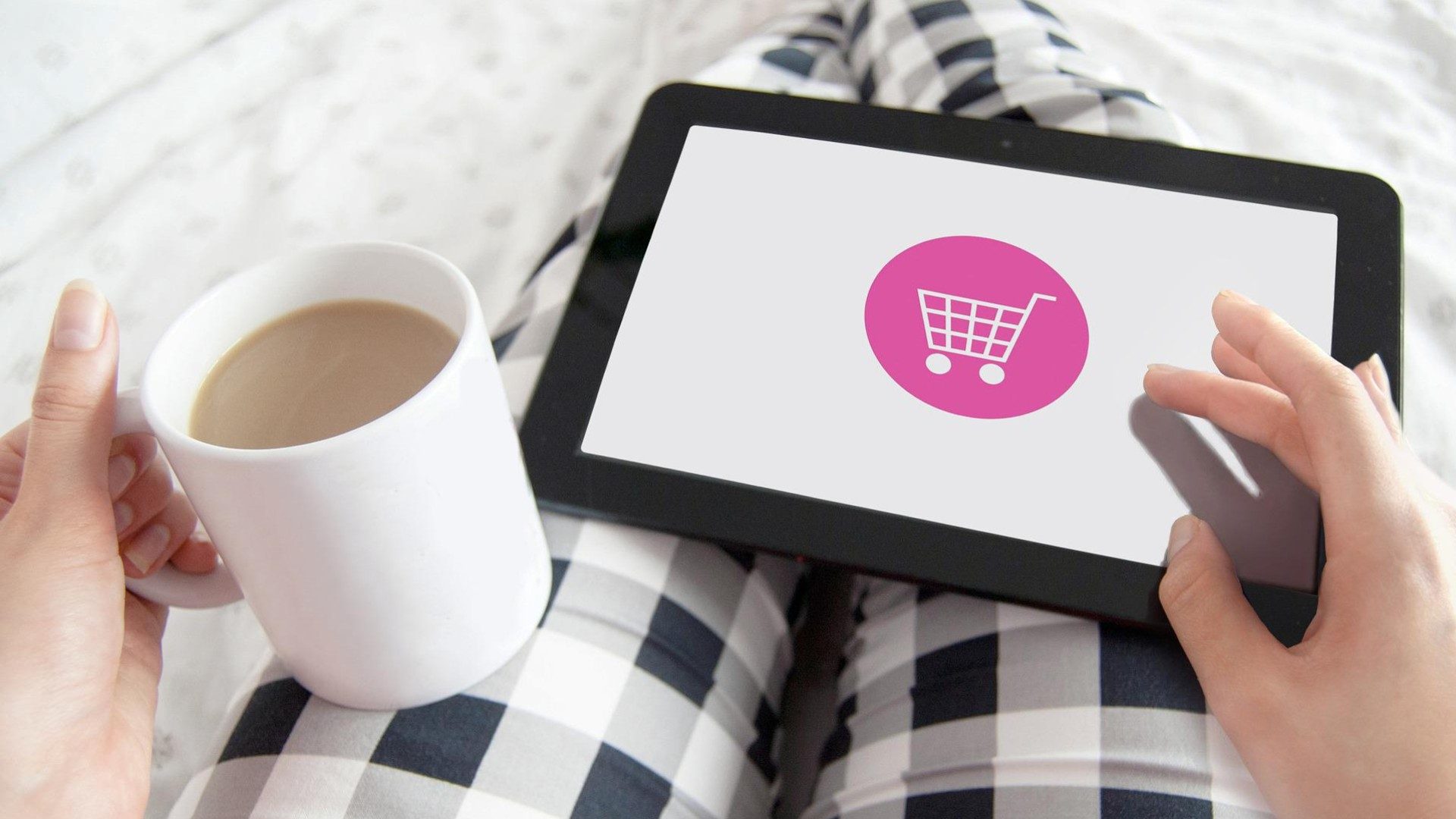 Eine Person kauft mit einem Kaufe auf einem Tablet ein. Auf dem Tablet ist ein Einkaufswagen abgebildet.