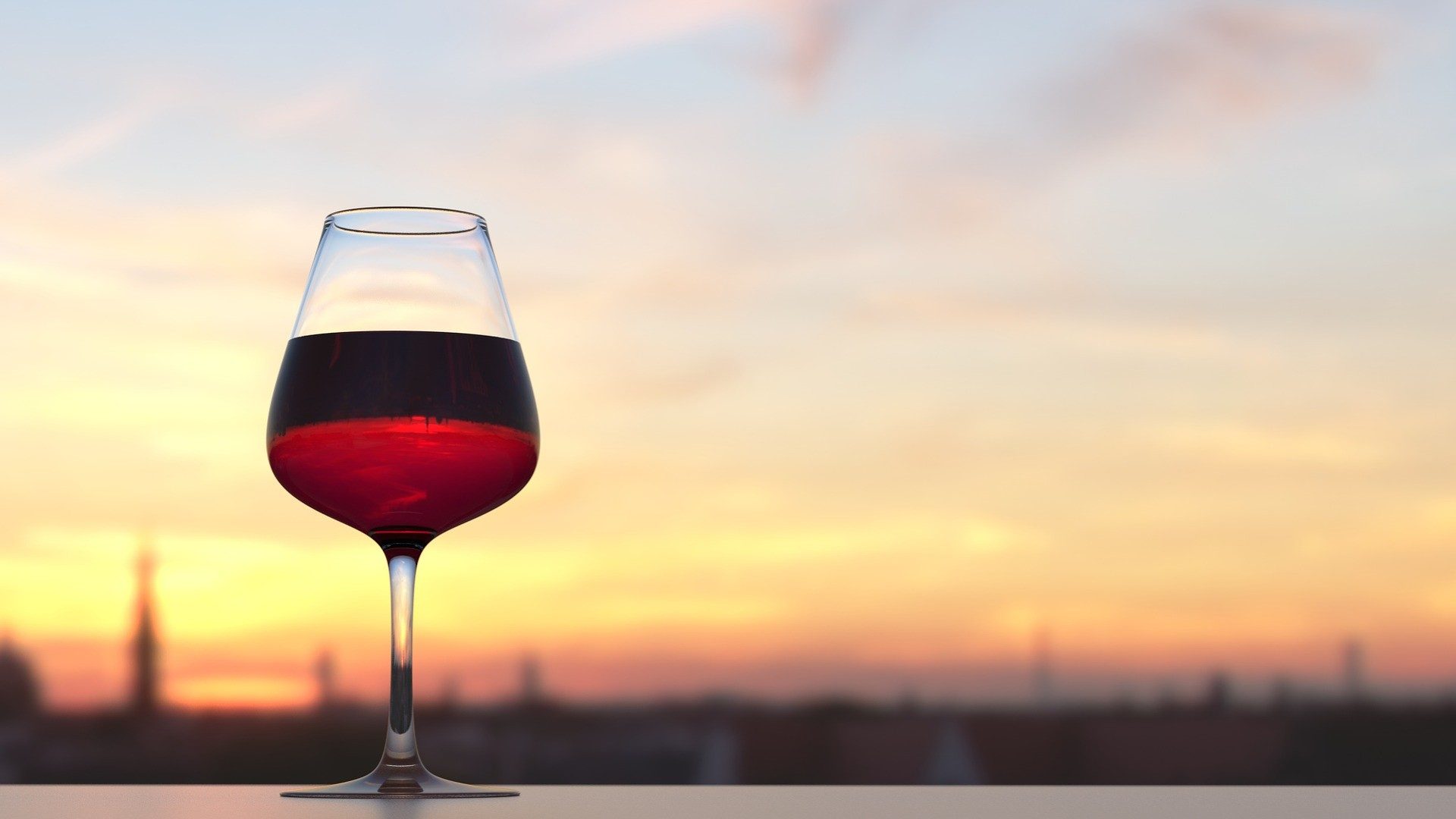 Ein Glas Wein vor einem Sonnenuntergang.