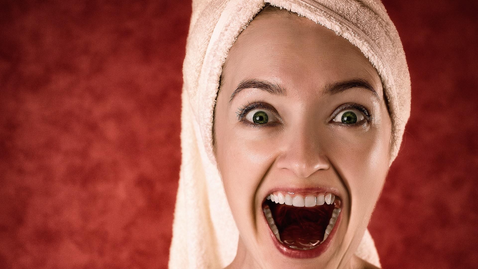 Eine Frau mit einem Handtuch um den Kopf ist überrascht.