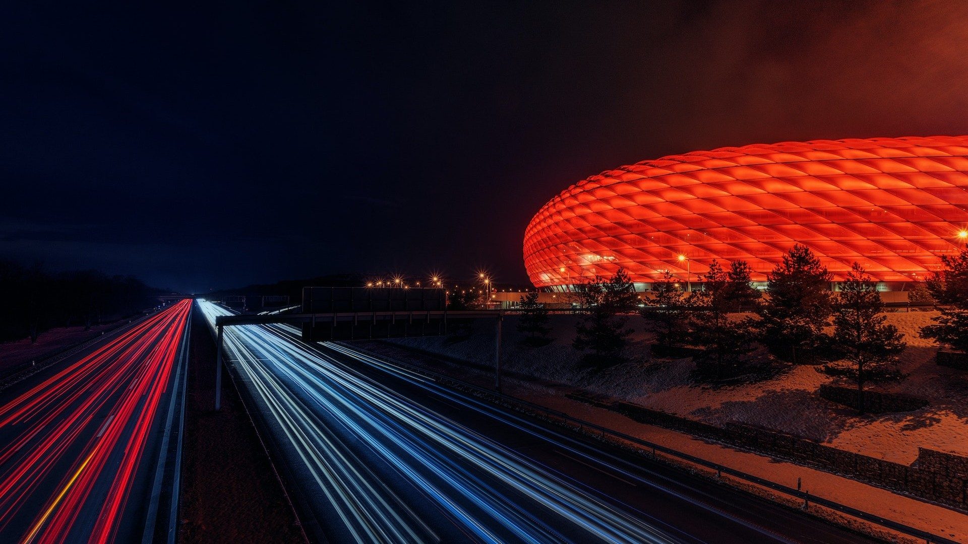Langzeitaufnahme der rot leuchtenden Allianz Arena des FC Bayern München bei Nacht
