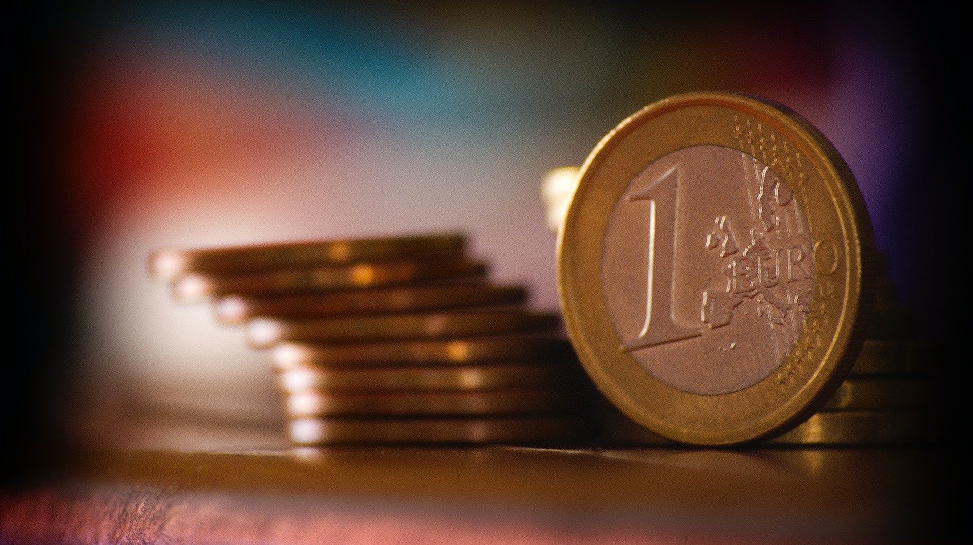 Eine Ein-Euro-Münze vor zwei Stapeln weiterer Geldmünzen